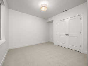 Unfurnished bedroom featuring light carpet and a closet