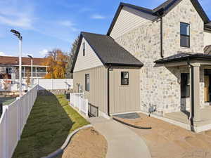View of property exterior featuring stone siding, a fenced backyard, and a standing seam roof