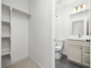Bathroom with vanity, dark tile patterned flooring, and a shower