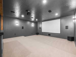 Home theater featuring a textured ceiling and light carpet