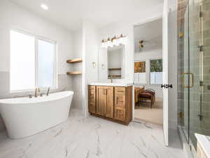 Full bath with vanity, tile walls, light marble finish flooring, a freestanding bath, and a shower stall