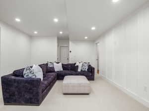Living area with carpet, recessed lighting, and a decorative wall