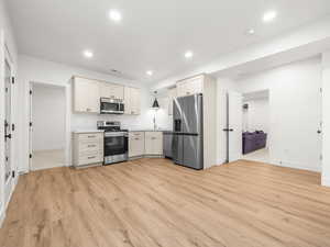 Kitchen featuring appliances with stainless steel finishes, light countertops, light wood-style floors, recessed lighting, and white cabinets