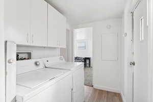 Laundry area with cabinet space, light wood finished floors, and washer and dryer