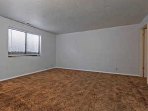 Empty room with dark carpet and a textured ceiling