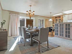 Dining space featuring light carpet, crown molding, and a chandelier