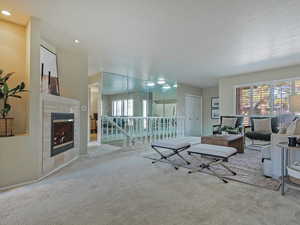 Carpeted living area with a tiled fireplace and recessed lighting