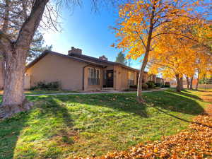 Front of house featuring a chimney, a yard, and brick siding
