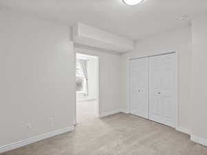 Unfurnished bedroom featuring light colored carpet and a closet