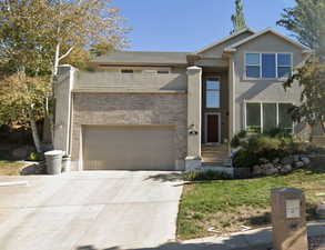 View of front of home featuring stucco siding, brick siding, and concrete driveway