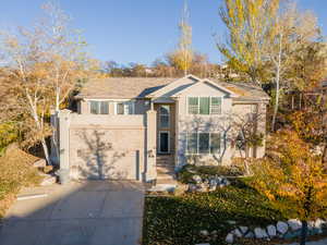 View of front of home with driveway, stucco siding, a garage, and brick siding