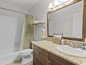 Bathroom featuring shower / bath combo with shower curtain, vanity, and light tile patterned floors