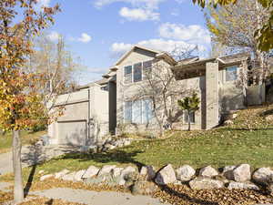 View of front of house with stucco siding, driveway, a garage, and a front yard