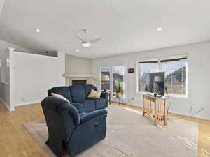 Living room featuring light wood finished floors, ceiling fan, recessed lighting, and a tiled fireplace
