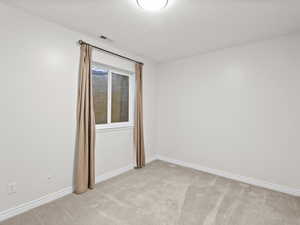 Spare room with light carpet and baseboards