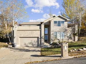 View of front of house featuring concrete driveway, stucco siding, a garage, and brick siding