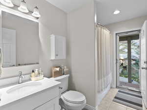 Full bath with a shower with shower curtain, light tile patterned floors, and vanity
