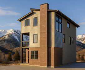 View of home's exterior with a mountain view, a balcony, a chimney, and brick siding
