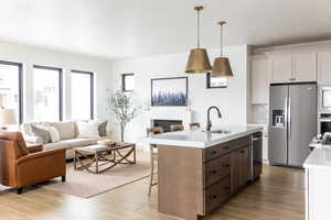 Kitchen featuring a kitchen bar, open floor plan, stainless steel appliances, an island with sink, and white cabinetry