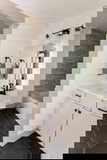 Bathroom featuring dark tile patterned floors, vanity, and a tub to relax in