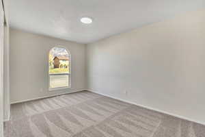 Carpeted spare room featuring baseboards