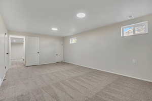 Below grade area with light colored carpet and healthy amount of natural light