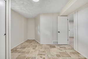 Below grade area with light stone finish flooring and a textured ceiling