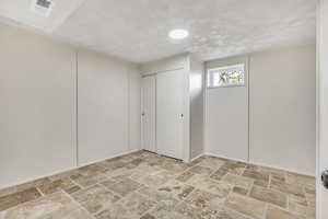 Below grade area featuring light stone finish floors and a textured ceiling