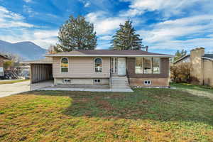Single story home featuring a front lawn, driveway, a mountain view, and brick siding