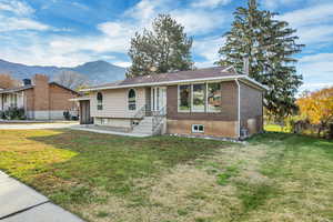 Ranch-style home featuring brick siding, a front yard, and a mountain view