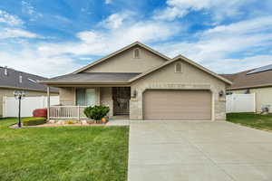 Single story home featuring stucco siding, a porch, an attached garage, driveway, and brick siding