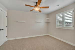 Carpeted empty room featuring baseboards and a ceiling fan