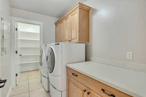 Laundry room featuring light tile patterned flooring, cabinet space, and independent washer and dryer