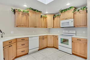 Kitchen featuring light brown cabinets, white appliances, light tile patterned flooring, light countertops, and recessed lighting