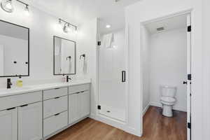 Full bath featuring a stall shower, light wood-type flooring, double vanity, and recessed lighting