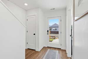 Foyer with light wood finished floors and recessed lighting