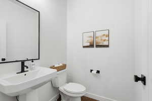 Half bathroom with toilet and dark wood-type flooring