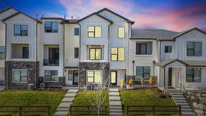 Modern farmhouse style home with a residential view, board and batten siding, stone siding, and a yard