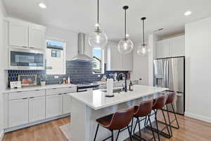 Kitchen with tasteful backsplash, stainless steel appliances, light wood-type flooring, and recessed lighting