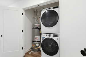 Laundry room featuring water heater, wood finished floors, and stacked washer / dryer
