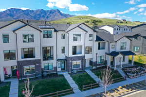 Modern farmhouse style home with board and batten siding, stone siding, a front lawn, and a mountain view