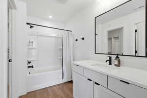 Bathroom featuring shower / bathtub combination with curtain, vanity, light wood-type flooring, a textured ceiling, and recessed lighting