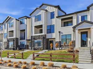View of front facade with board and batten siding, stone siding, and a front lawn