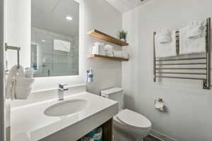 Full bath with radiator, vanity, a towel warmer, a shower stall, and recessed lighting