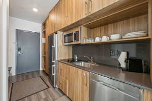 Kitchen featuring open shelves, stainless steel appliances, dark wood-type flooring, modern cabinets, and dark stone counters