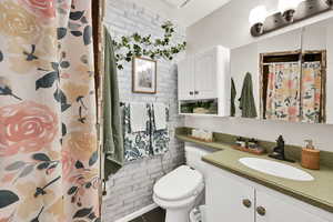 Master Bathroom featuring a shower with curtain, vanity, dark tile patterned flooring, and brick wall