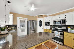 Kitchen featuring tasteful backsplash, stainless steel appliances, dark stone counters, light tile patterned floors, and a kitchen breakfast bar