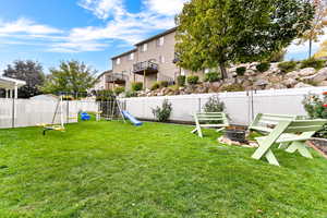 Fenced backyard featuring a playground and a fire pit