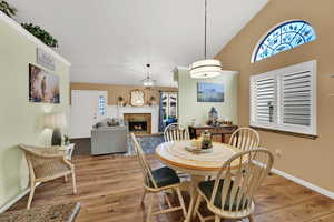 Dining room featuring a lit fireplace, light wood-type flooring, and high vaulted ceiling