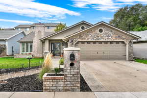 View of front of home featuring concrete driveway, stone siding, and an attached garage